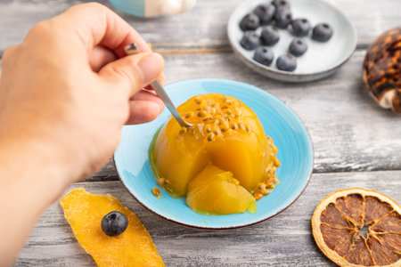 Mango and passion fruit jelly with blueberry with hand on gray wooden background. side view, close up, selective focus.の写真素材
