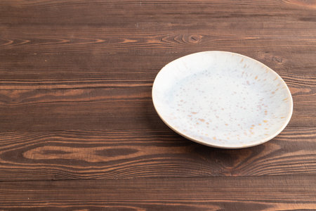 Empty blue and gold ceramic plate on brown wooden background. Side view, copy space.の写真素材