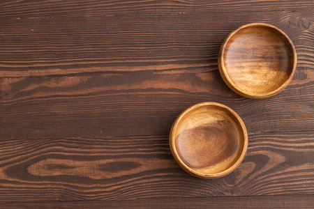 Two empty brown wooden bowl on brown wooden background. Top view, copy space, flat lay.の写真素材
