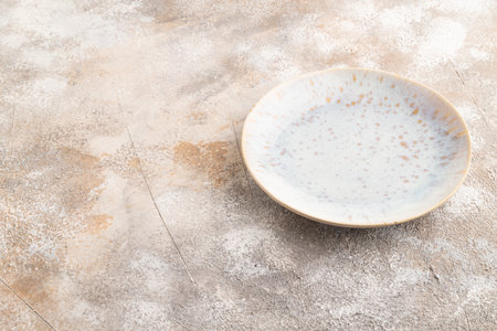 Empty blue and gold ceramic plate on brown concrete background. Side view, copy spaceの写真素材