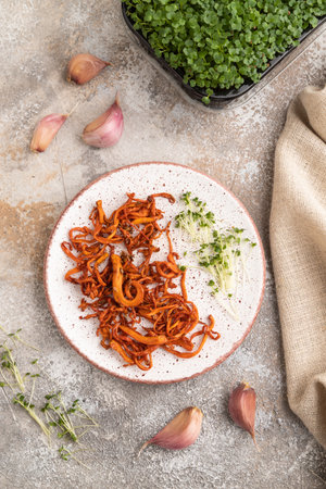 Fried Cordyceps militaris mushrooms on brown concrete background with microgreen, herbs and spices. Top view, flat lay, close up.の写真素材