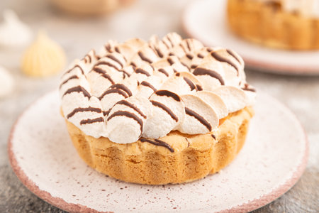 Two tartlets with meringue cream and cup of coffee on brown concrete background. side view, selective focus. Breakfast, morning, concept.の写真素材