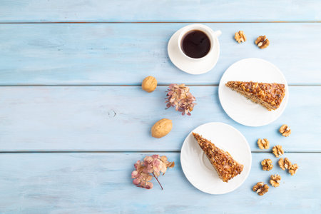 Walnut and hazelnut cake with caramel cream, cup of coffee on blue wooden background. top view, flat lay, copy space.の写真素材