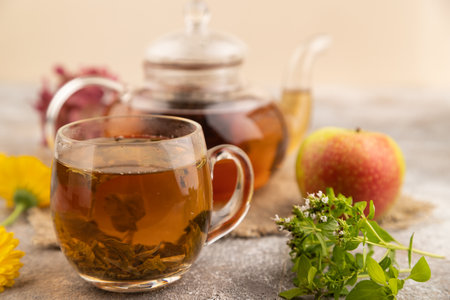 Red tea with herbs in glass teapot on brown concrete background and linen textile. Healthy drink concept. Side view, close up, selective focus.の写真素材