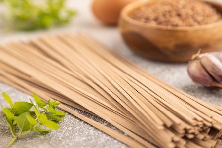 Japanese buckwheat soba noodles with tomato, eggs, spices, herbs on brown concrete background. Side view, close up, selective focus.の写真素材
