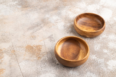 Two empty brown wooden bowl on brown concrete background. Side view, copy spaceの写真素材