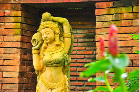 A woman statue in park with warm sunset light.