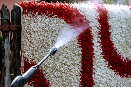 Cleaning the carpet with a gun for washing high pressure water. House cleaning. Outdoors.