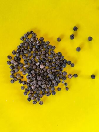 Pile of black pepper on yellow backgroundの写真素材