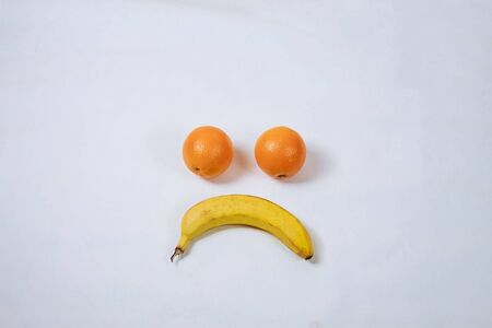 orange and banana, forming a smiley, isolated on white. Smile. Sadness.の写真素材