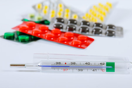 Thermometer with a blister of different pharmacy pills.