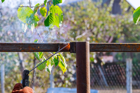 Electric welder makes the fence in manor. Welder welding a fence in the street.