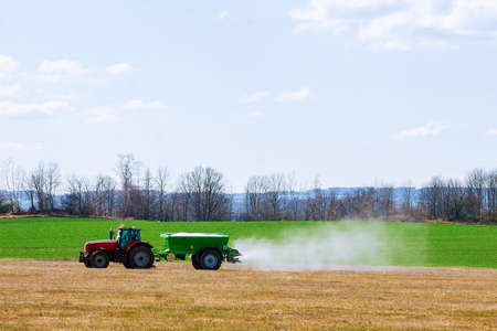 Agricultural work. Tractor spreading fertilizer on grass field.のeditorial素材