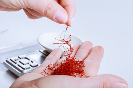 Weighing saffron threads on a digital jewelry scale on a white background