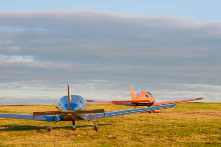 Blur Light small plane on a grass field on a background of blue cloudsの写真素材