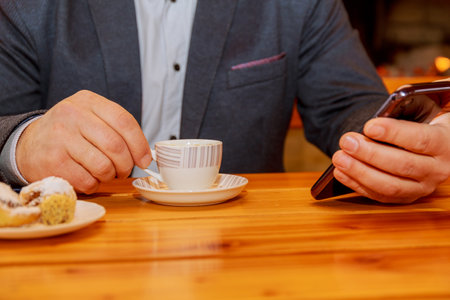 Man using a cell phone and drinking coffee.の写真素材