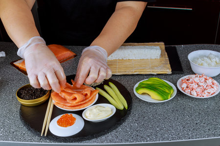 Woman using bamboo rolling mat for home made sushiの写真素材