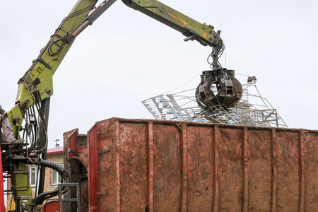 A grapple truck loads scrap industrial metal for recycling.の写真素材