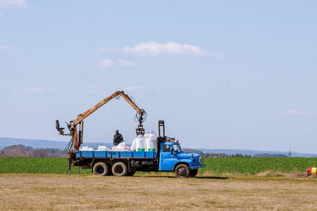 Agricultural work. Tractor spreading fertilizer on grass field.の写真素材