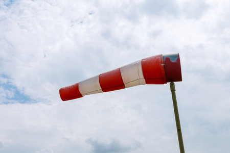 A large red white striped windsock against blue sky