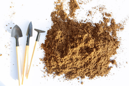 Plastic pots are filled with peat. Heap of soil and gardening tools on a white background. Preparation for sowing seeds.の写真素材