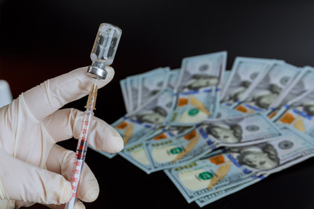 Vaccination covid-19. The nurse draws the vaccine from the vial into the syringe. Insurance pays for the vaccine in dollars.の写真素材