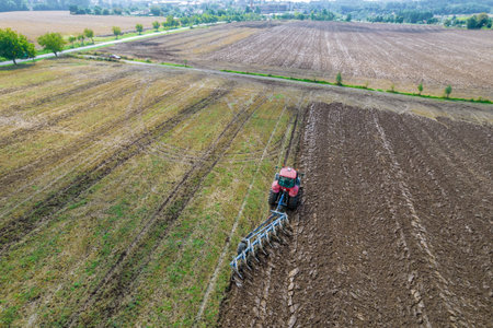 Plowing the ground with a tractor to which a plow is attached, aerial view.