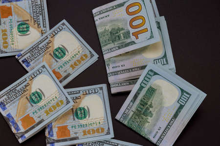 Many one hundred dollar bills lie on a black background.の写真素材