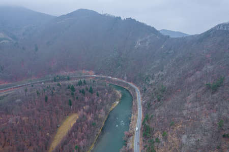 Mountain road near the river, a village in the forest. View from aboveの写真素材