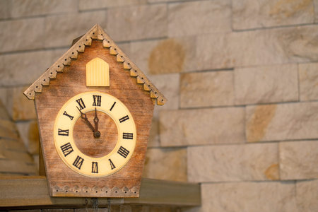 Cuckoo clock decorates a stone wall. Its almost twelve oclock on the clock.