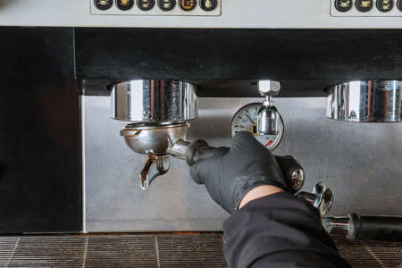 The girl unscrews the holder from the coffee machine to pour out the used coffee.の写真素材