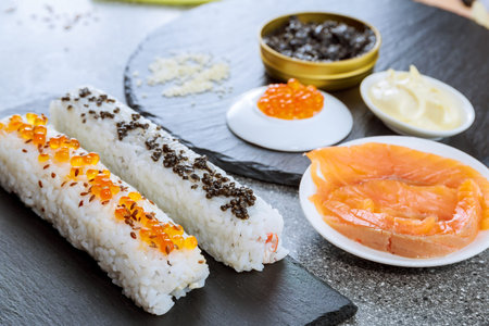 On black plates - sushi rolls sprinkled with black and red caviar. Sushi with seafood. Sushi itself is a balanced meal.の写真素材