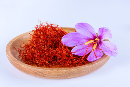 Saffron stamens and crocus in a wooden plate on a white background. Place for text.の写真素材