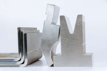 Equipment for bending sheet metal on a CNC bending machine on a white background. Matrix and curved productの写真素材