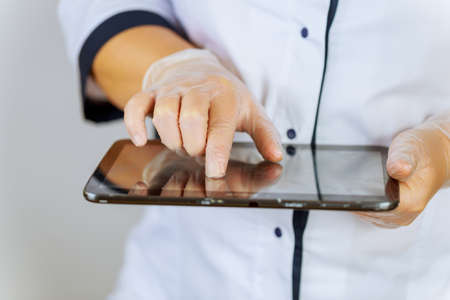 Female doctor writes notes on tablet on clipboard at hospital. Prescribe treatment to patients to improve their well-being.の写真素材