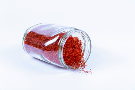 Saffron in a glass jar on a white background. Red saffron stamens.