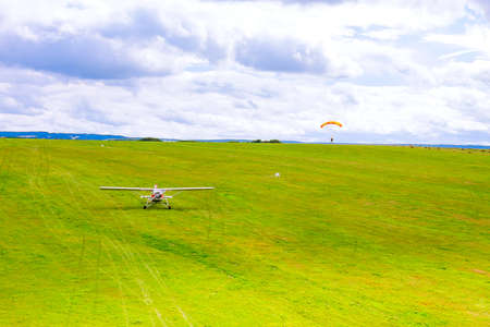 Small plane on a green field, paratrooper landing on a green field. air entertainment. view from above.の写真素材