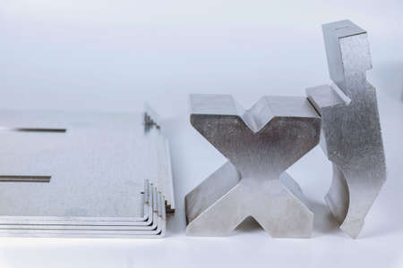 Equipment for bending sheet metal on a CNC bending machine on a white background. Matrix and curved productの写真素材