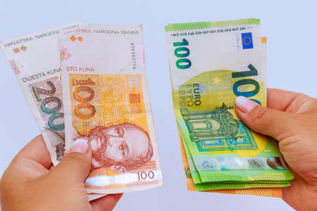Euro and kuna in the hands of a banker close-up on a white background. banknotes of different denominations.の写真素材