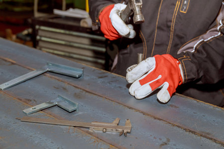 Marking tools. markings on a metal surface for drilling holes. The worker makes a mark on a metal surface. Drilling holes in metal profiles for mounting metal structures.の写真素材