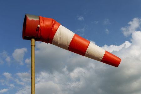 A large red white striped windsock against blue sky