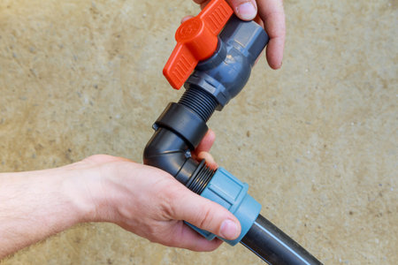 A plumber installs a faucet on a polyethylene pipe.