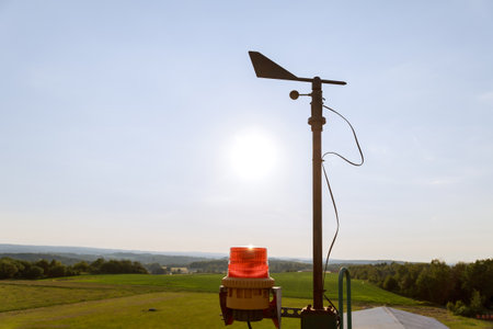 A windmill and a broken anemometer on the towers of a small airport.の写真素材