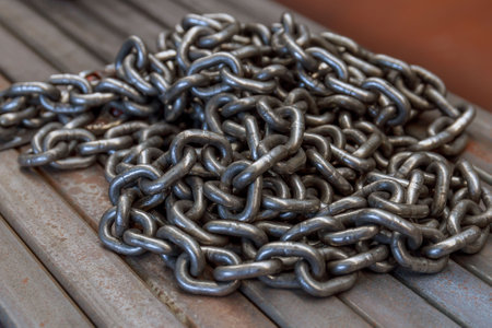 A pile of chain rests on a bundle of rolled metal pipe.の写真素材