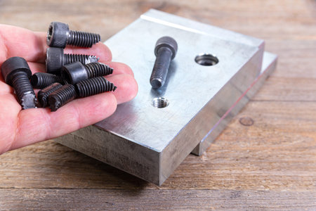 Broken black bolts in workers hand. Bolt with a hexagonal head.