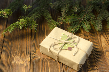 Gift box in kraft paper, brunch of fir on a wooden backgroundの写真素材