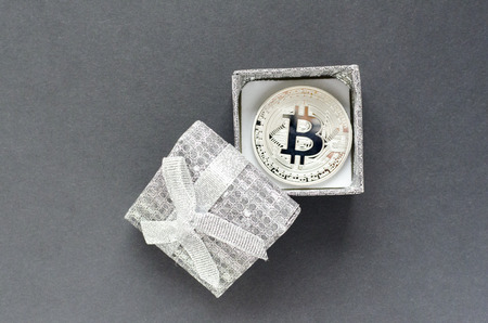 Silver bitcoin and gift box on gray backgroundの写真素材