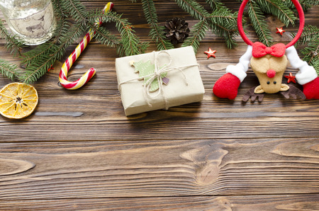 christmas background: toy deer, gift box, fir, candy on wooden tableの写真素材