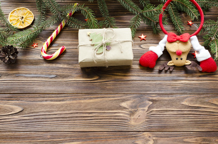 christmas background: toy deer, gift box, fir, candy on wooden tableの写真素材