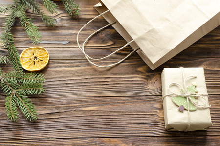 gift box and kraft paper bag on wooden table decorated fir and dry orangeの写真素材